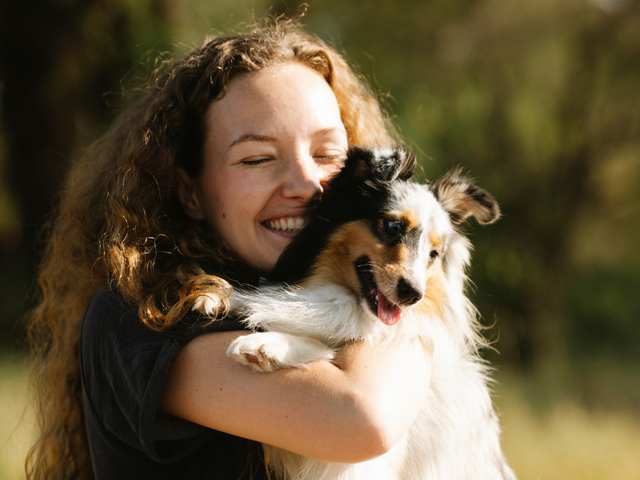 Young lady hugging Sheltie smiling because she has a career with a Pet Station location in Nevada or California