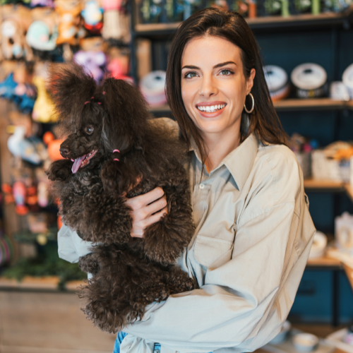 Happy woman holding chocolate poodle  - Pet Station's mission statement Tahoe, NV