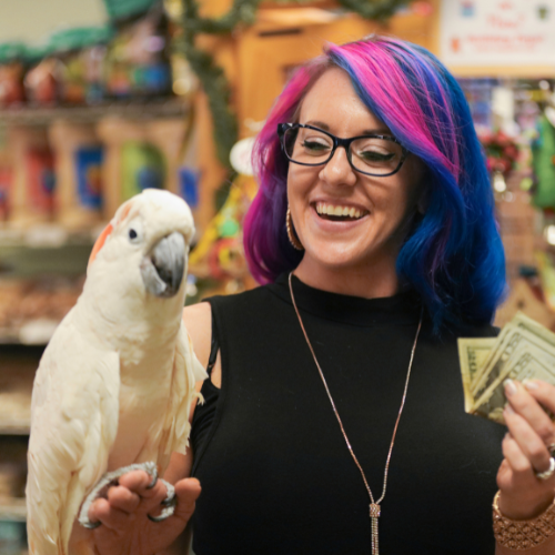 Woman holding Cockatoo on one hand money in the other for employee perks at Pet Station in Tahoe, NV